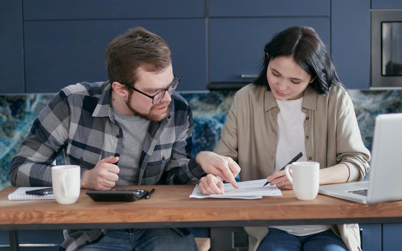 Interracial couple discussing bills and financial planning in a cozy indoor setting.