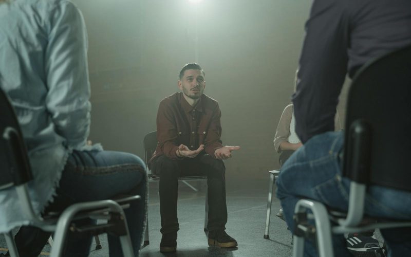 A group therapy session indoors with diverse adults in a supportive environment.
