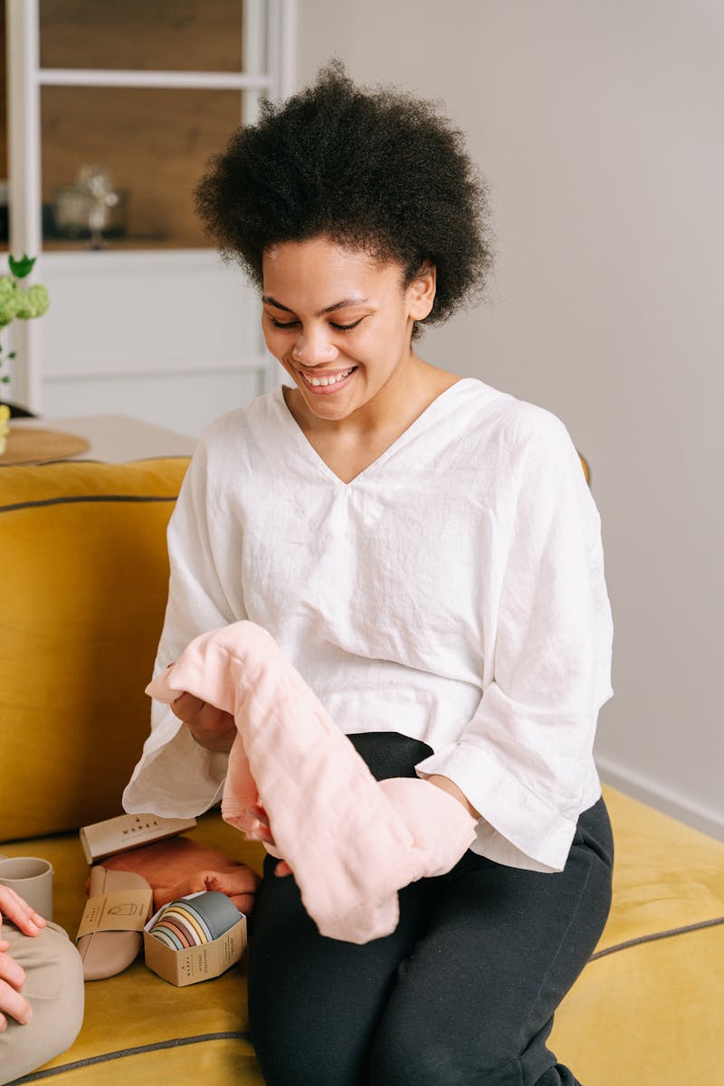 Joyful African American woman receiving baby shower gift indoors, filled with happiness and excitement.